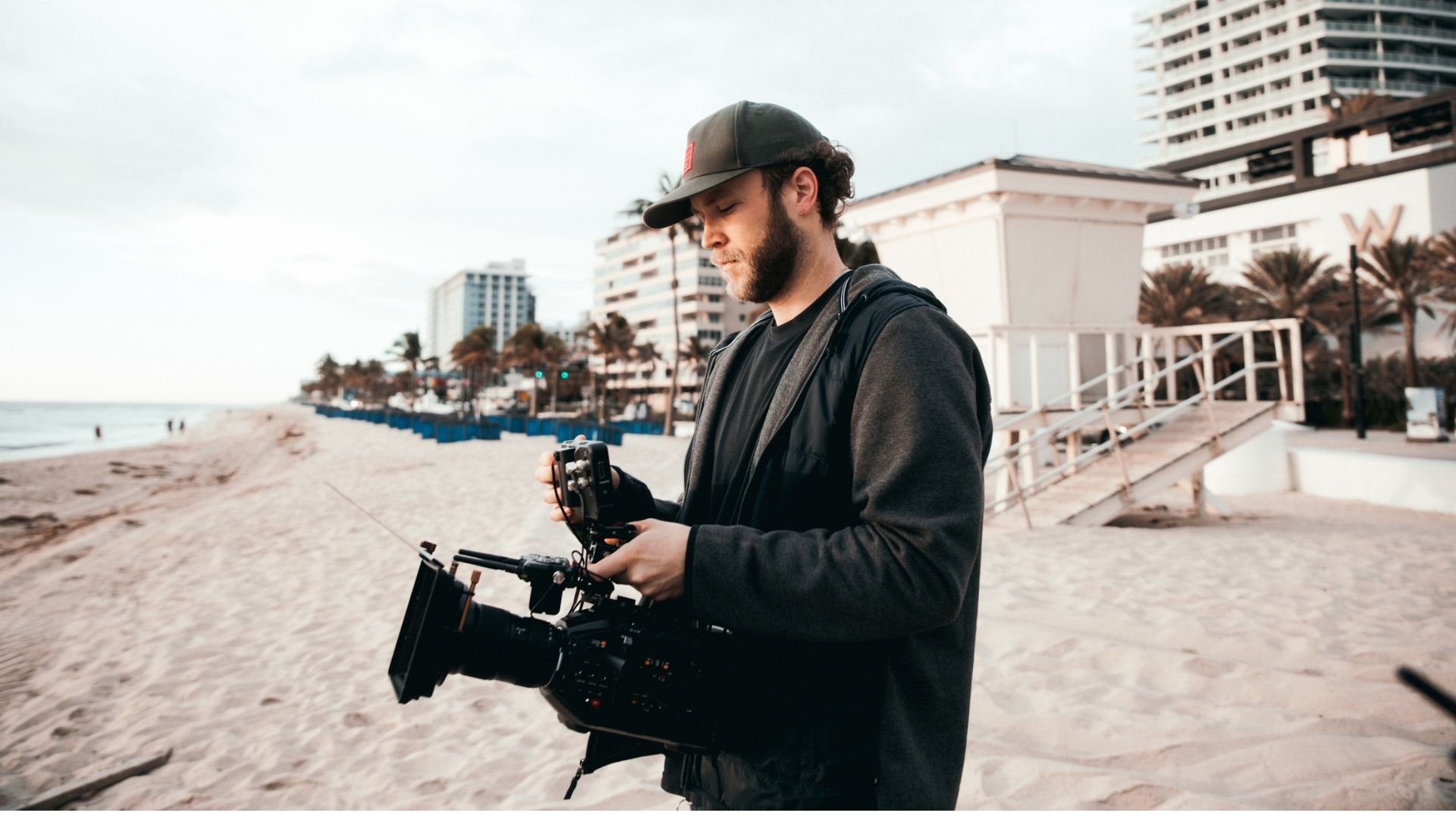 man filming on a beach location with the W hotel behind him